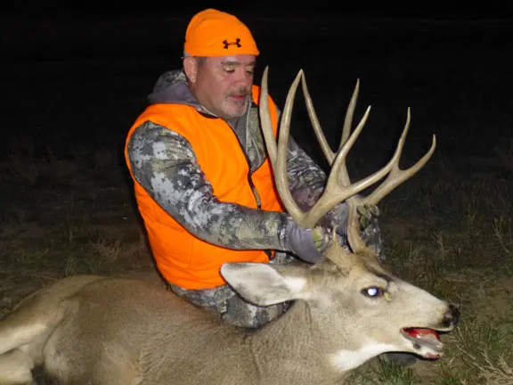Hunter in blaze orange with a mule deer buck, 2017